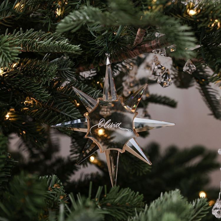 Engraved crystal star Christmas ornament hanging on a green Christmas tree