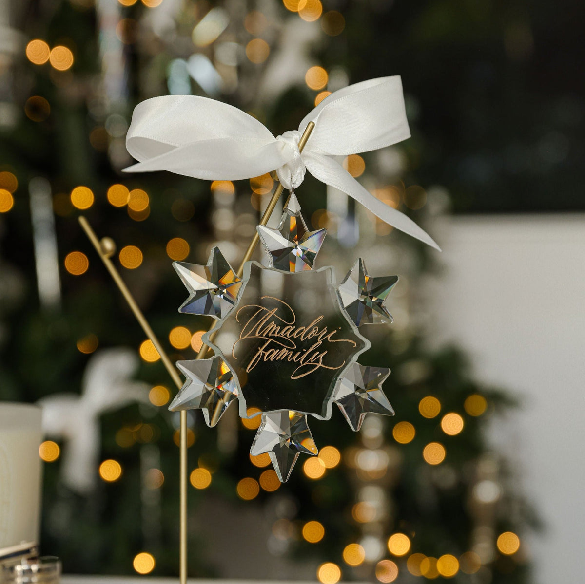 Engraved crystal snowflake ornament for the Maddox family on a gold stand with white satin ribbon