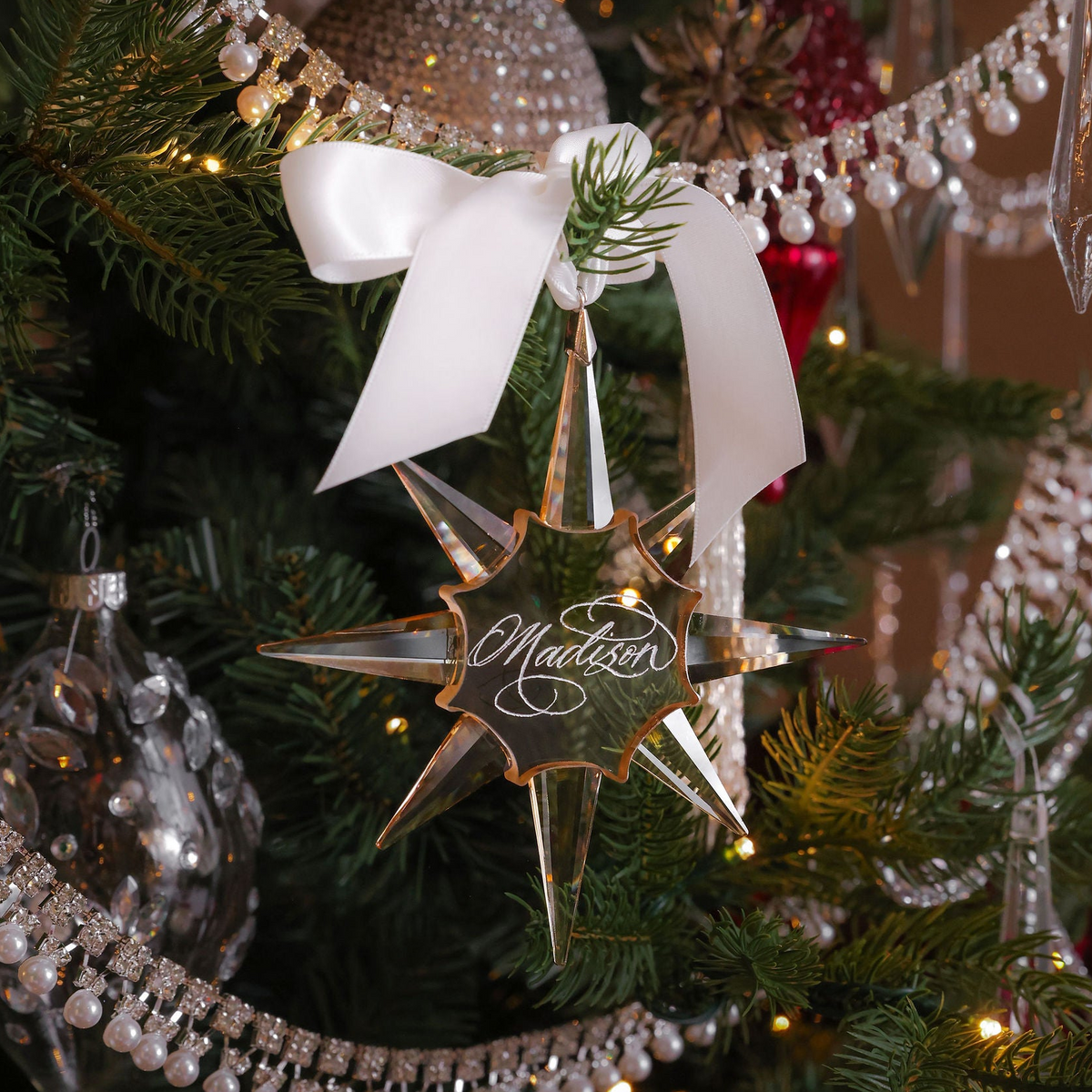 Opulent calligraphy engraved gold crystal star ornament with white ribbon on a Christmas tree