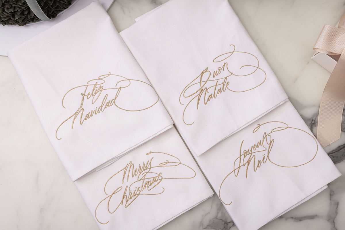 Embroidered Christmas napkins in metallic gold thread in four languages