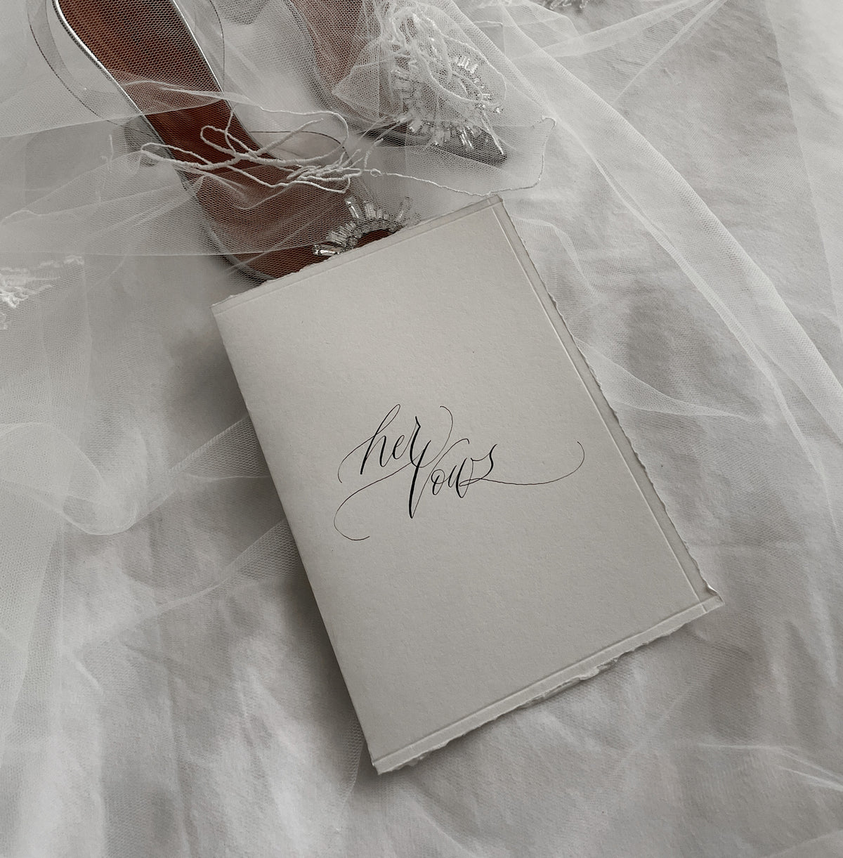 Her vows calligraphy vow book on a bridal veil