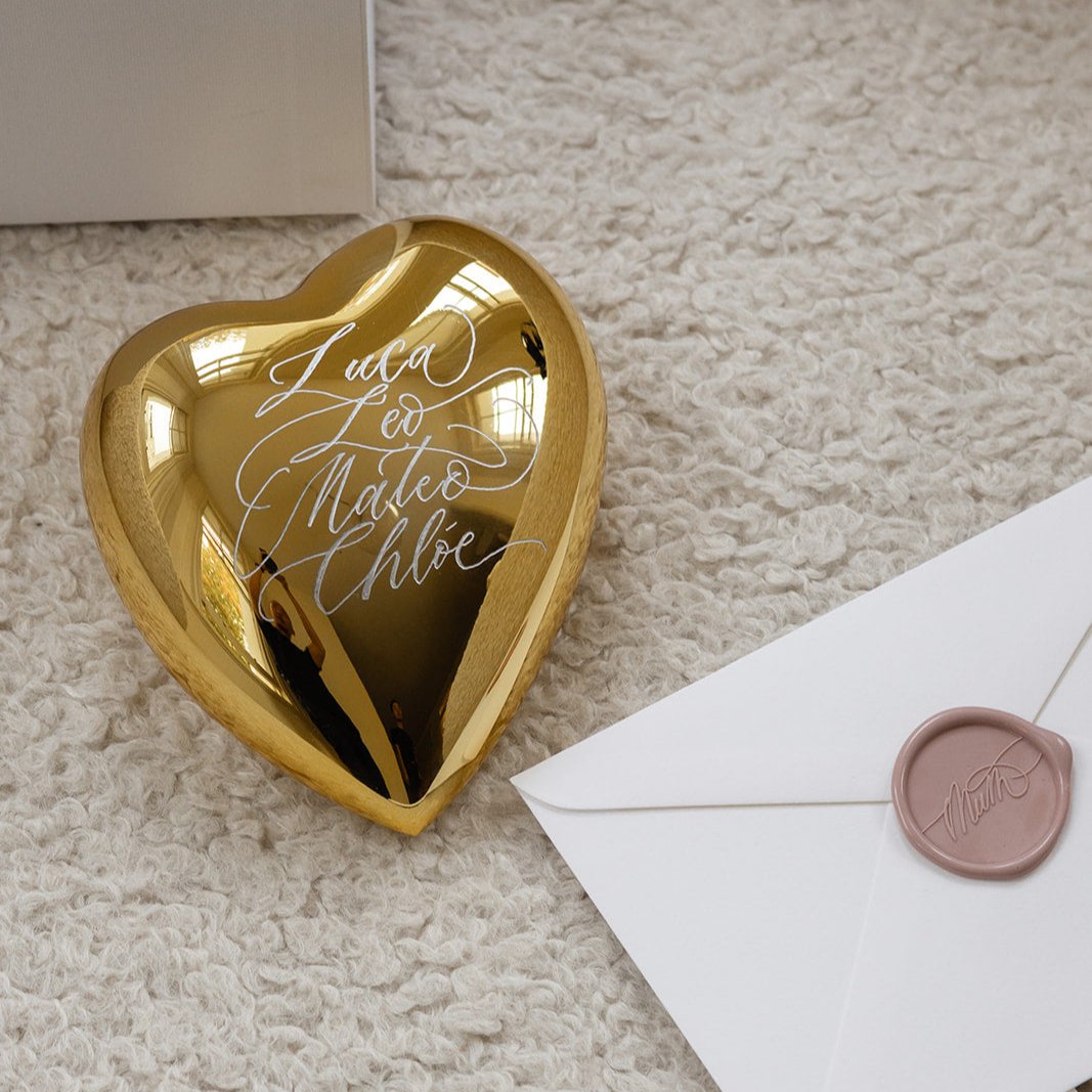 Personalised gold crystal heart engraved with children's names beside a wax-sealed envelope