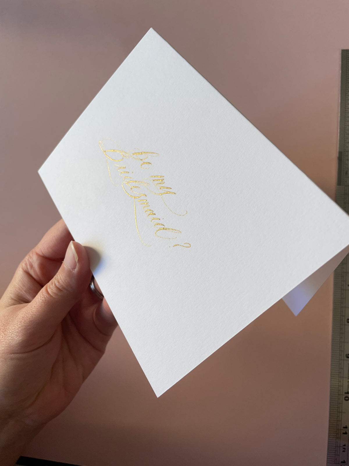 Gold ink, hand lettered Be my Bridesmaid card held in hand