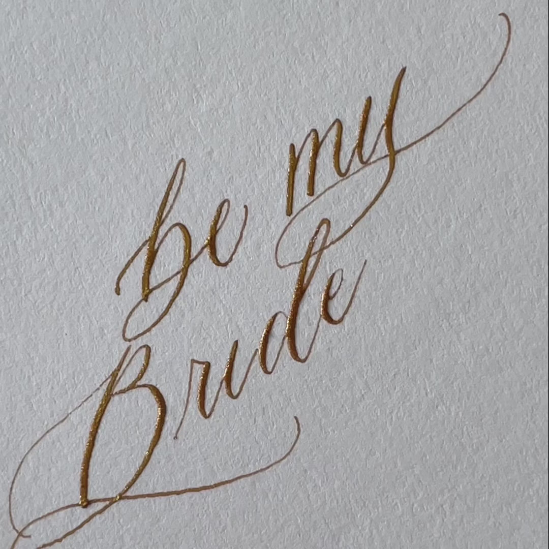Load video: Gold ink, handwritten calligraphy being written on a bridesmaid proposal card